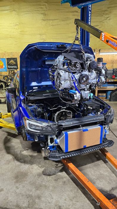 Built engine being lowered into a blue Subaru